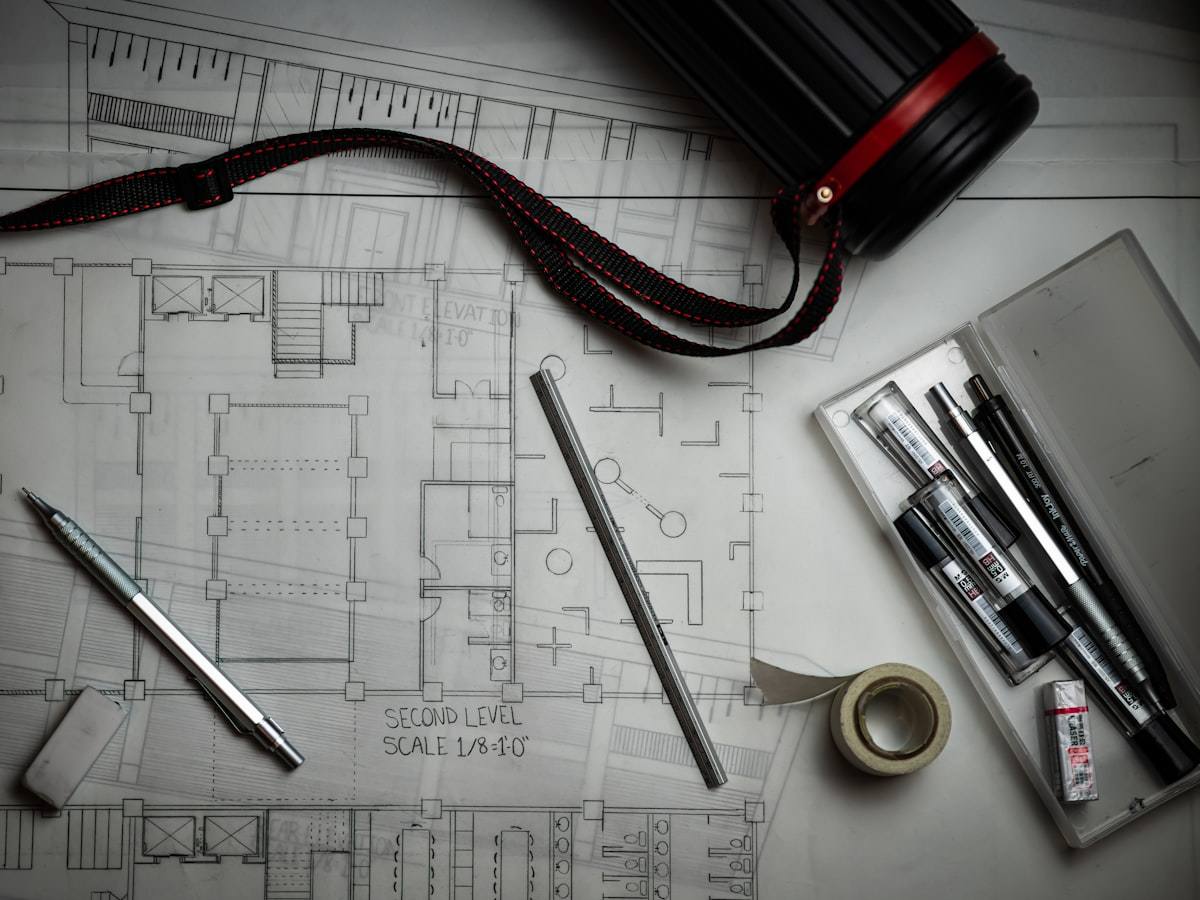 Tavolo di lavoro con elaborati progettuali e strumenti da disegno